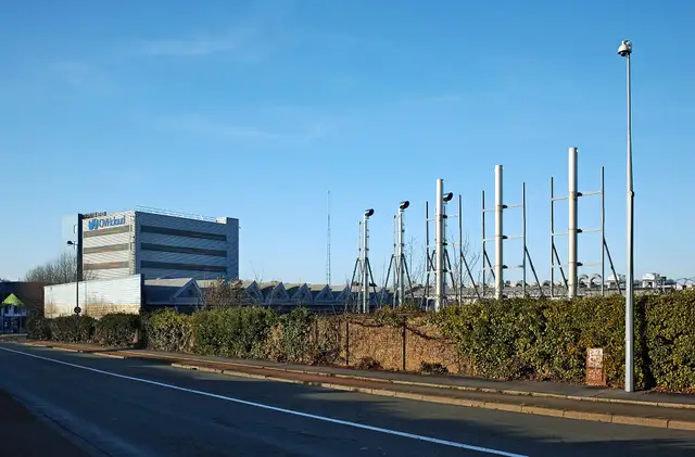 OVHcloud’s datacenter buildings in Roubaix seen from the street, behind a hedge and a row of poles.